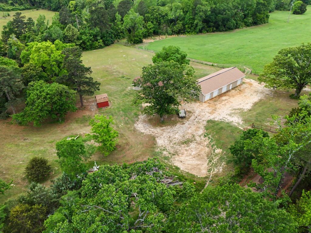1129 Holly Road Gilmer, TX 75644 - Photo 26 of 31 Expansive rural property featuring an outbuilding with multiple bays, a smaller red auxiliary structure, and a large open field