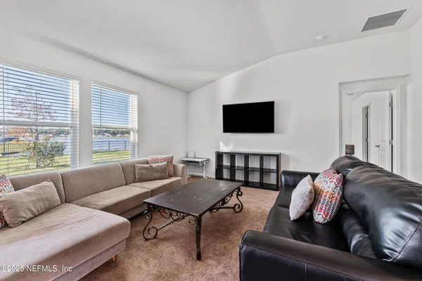 a living room with furniture a flat screen tv and kitchen view