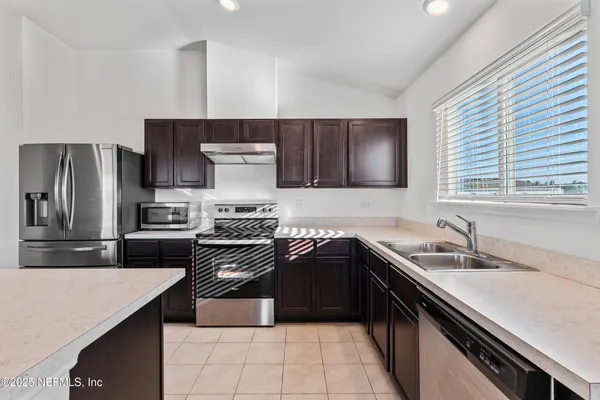 a large white kitchen with kitchen island a sink a stove a refrigerator and a refrigerator