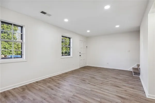 an empty room with wooden floor and windows