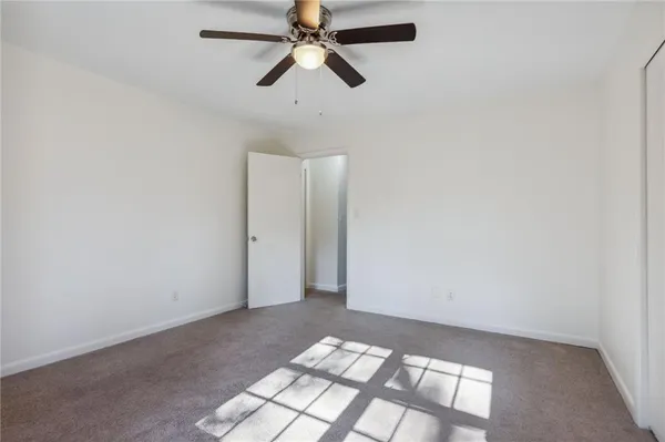 an empty room with a chandelier fan and windows