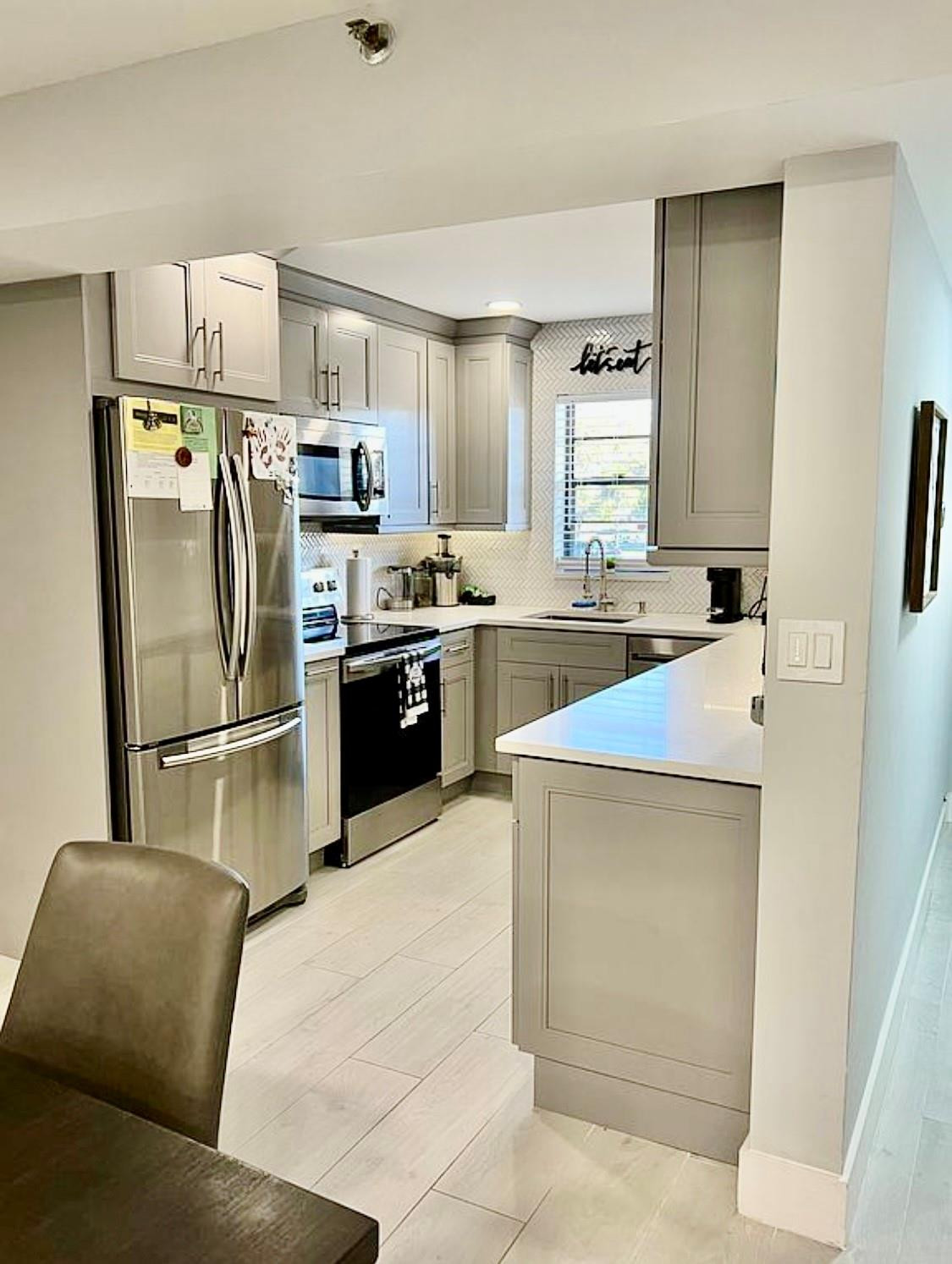 9235 Southwest 8th Street, Unit 207 Boca Raton, FL 33428 - Photo 3 of 24 a kitchen with stainless steel appliances a refrigerator a sink a stove a table and chairs