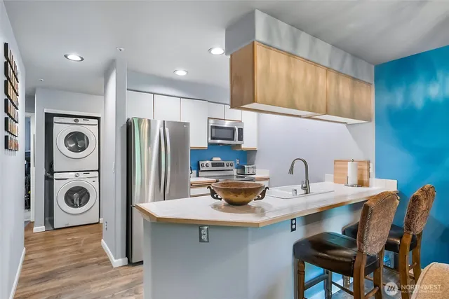 a kitchen with stainless steel appliances a sink a stove a refrigerator cabinets and dining table