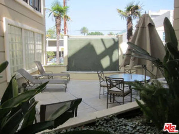 a view of a patio with couches table and chairs under an umbrella with a fire pit