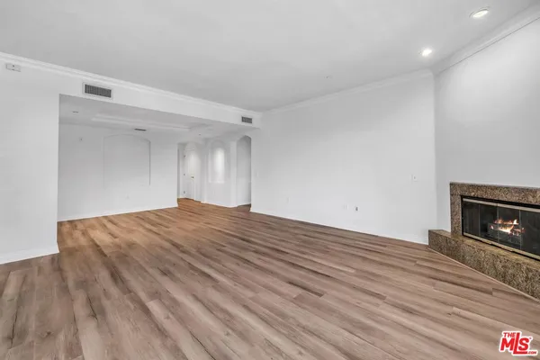 a view of empty room with wooden floor and fireplace