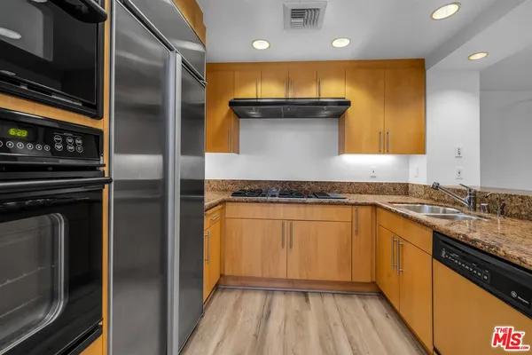 a kitchen with granite countertop stainless steel appliances and wooden floor