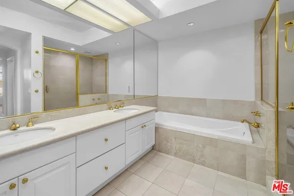 a spacious bathroom with a tub sink and mirror