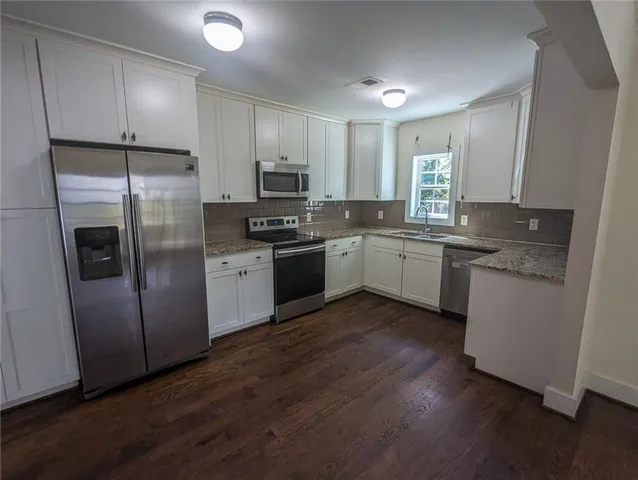 a kitchen with granite countertop a refrigerator and a stove top oven