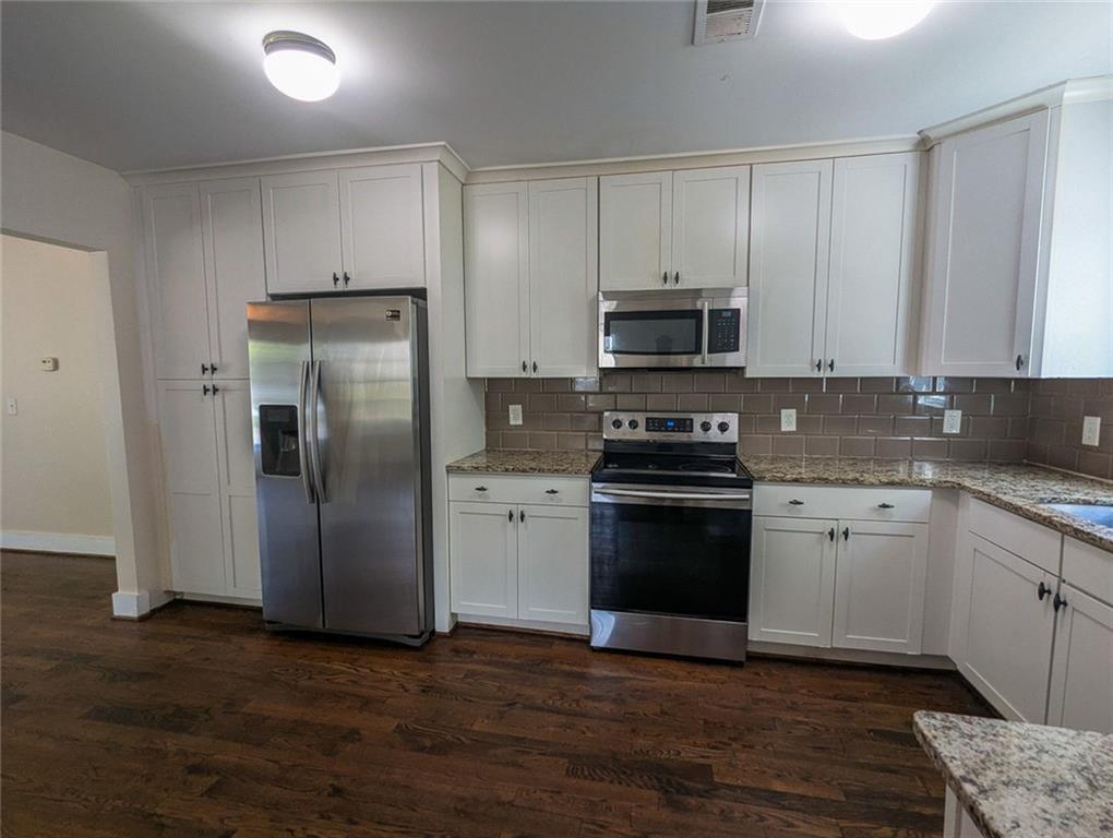 1261 Eastridge Road Southwest Atlanta, GA 30311 - Photo 15 of 36 a kitchen with granite countertop a refrigerator and a stove top oven
