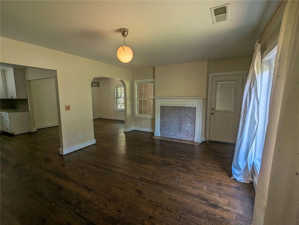 1261 Eastridge Road Southwest Atlanta, GA 30311 - Photo 9 of 36 an empty room with wooden floor and fireplace