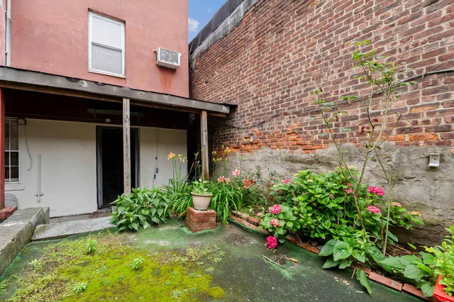 a view of a backyard with plants and brick wall