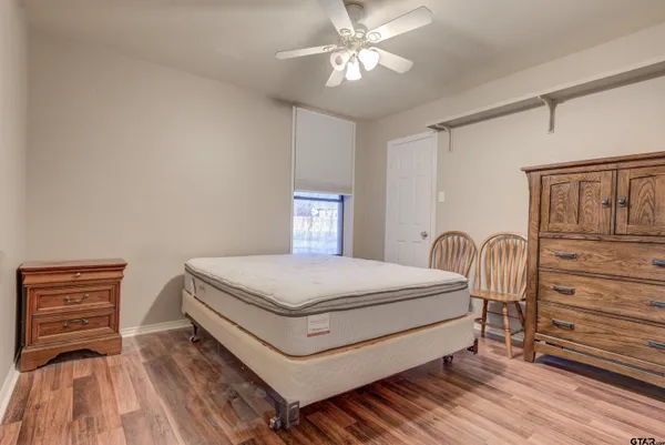 a bedroom with a bed and dresser with wooden floor