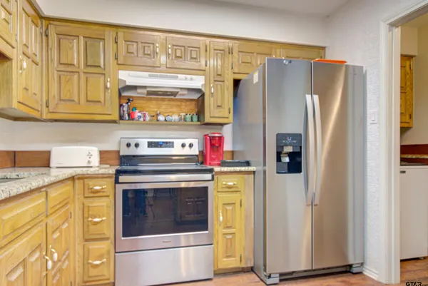 a kitchen with stainless steel appliances granite countertop a refrigerator and a stove