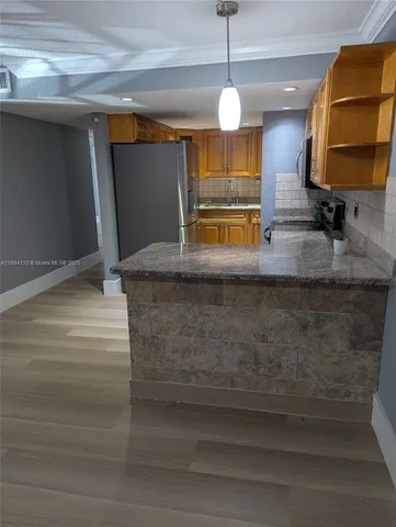 a kitchen with kitchen island granite countertop wooden cabinets and a sink
