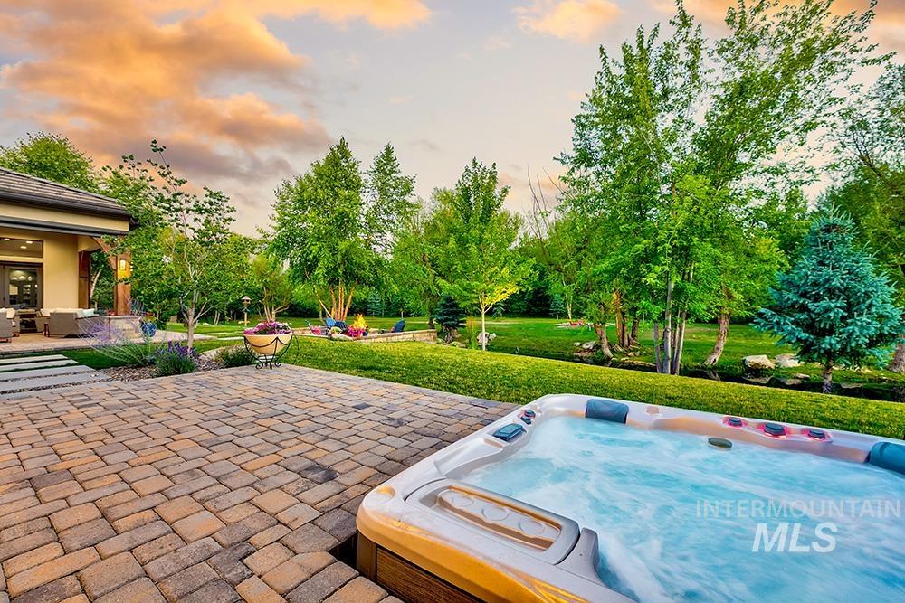 1582 East Rivers End Court Eagle, ID 83616 - Photo 23 of 49 Patio terrace at dusk with a yard, a hot tub, a patio, and view of wooded area