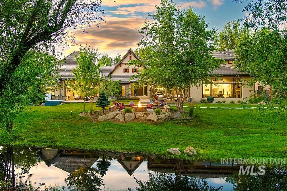 1582 East Rivers End Court Eagle, ID 83616 - Photo 46 of 49 Back of house at dusk featuring a patio, a fire pit, a lawn, stucco siding, and a water view