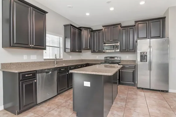 a kitchen with kitchen island granite countertop stainless steel appliances a sink stove and refrigerator