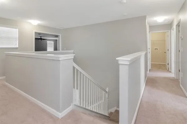 a view of a hallway with white walls and stairs