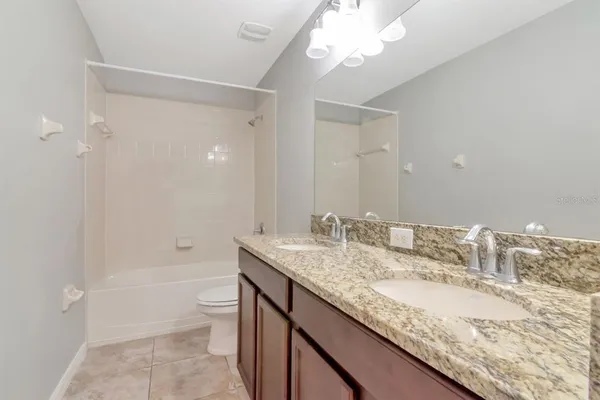 a bathroom with a granite countertop sink a toilet and bathtub