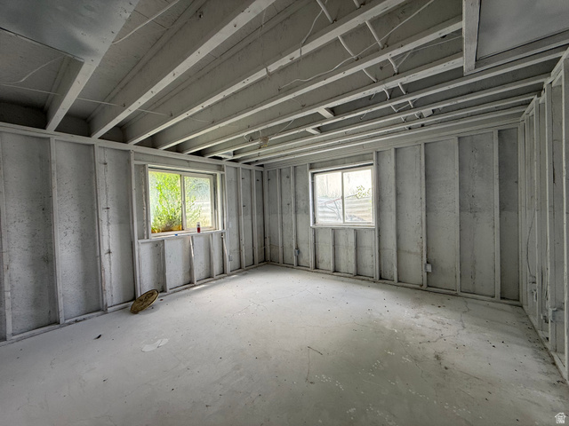 838 East Mountain Road Logan, UT 84321 - Photo 26 of 37 Unfinished room featuring exposed ceiling joists and framed walls, two windows with white trim, and a concrete floor