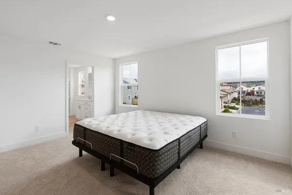 a bed sitting in a spacious bedroom next to a window