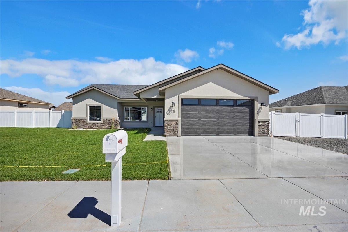 Single story home featuring stone siding, stucco siding, a garage, driveway, and a gate