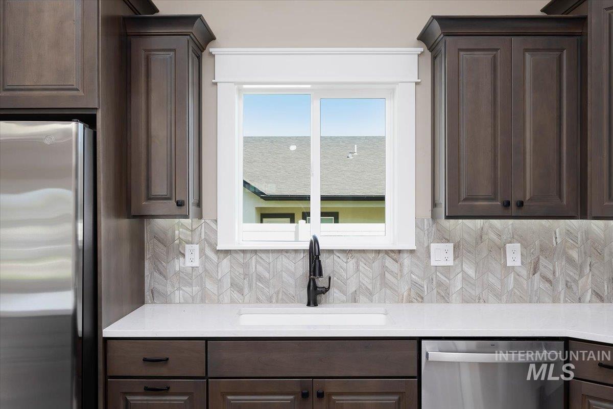 231 Sandi Road Twin Falls, ID 83301 - Photo 9 of 31 Kitchen featuring dark brown cabinets, stainless steel appliances, tasteful backsplash, and light stone counters