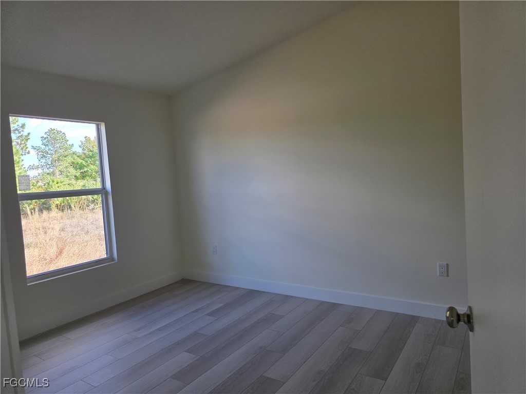2615 32nd Street Southwest Lehigh Acres, FL 33976 - Photo 12 of 19 an empty room with wooden floor and windows