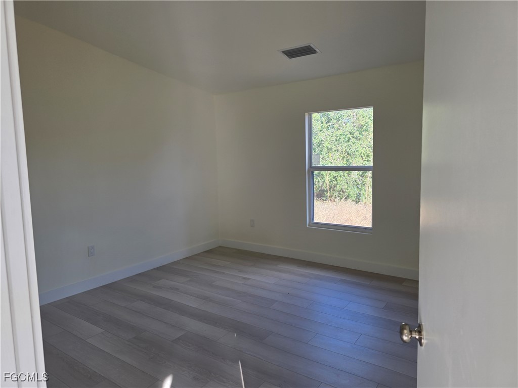 2615 32nd Street Southwest Lehigh Acres, FL 33976 - Photo 14 of 19 an empty room with wooden floor and windows