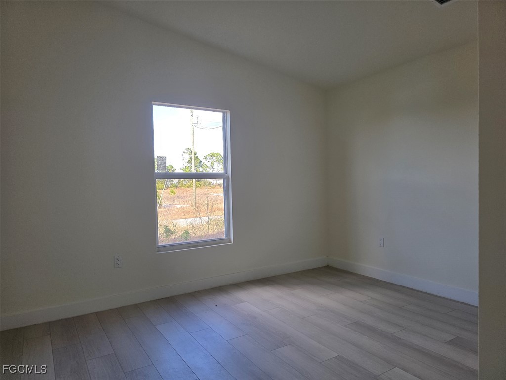 2615 32nd Street Southwest Lehigh Acres, FL 33976 - Photo 16 of 19 an empty room with wooden floor and windows