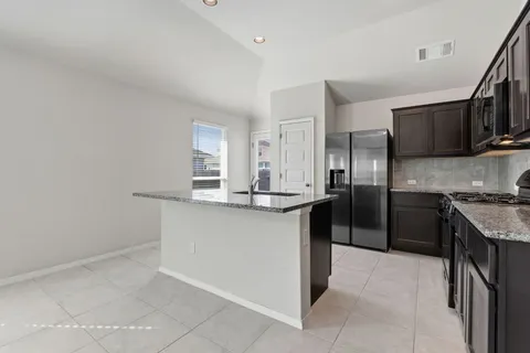 a kitchen with stainless steel appliances granite countertop a sink and a refrigerator