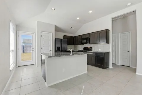 a kitchen with stainless steel appliances granite countertop a stove top oven a sink and a refrigerator