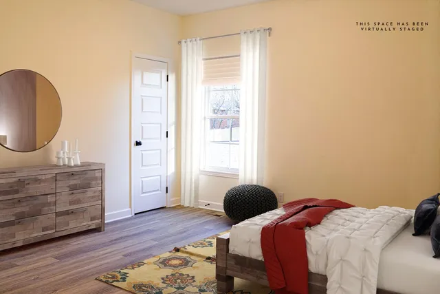a bedroom with a bed a dresser and wooden floor