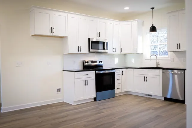 a kitchen with granite countertop white cabinets and white appliances