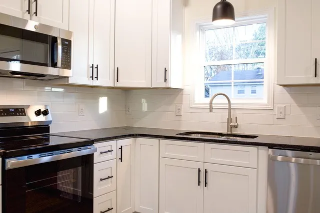 a kitchen with stainless steel appliances granite countertop a sink a stove and microwave