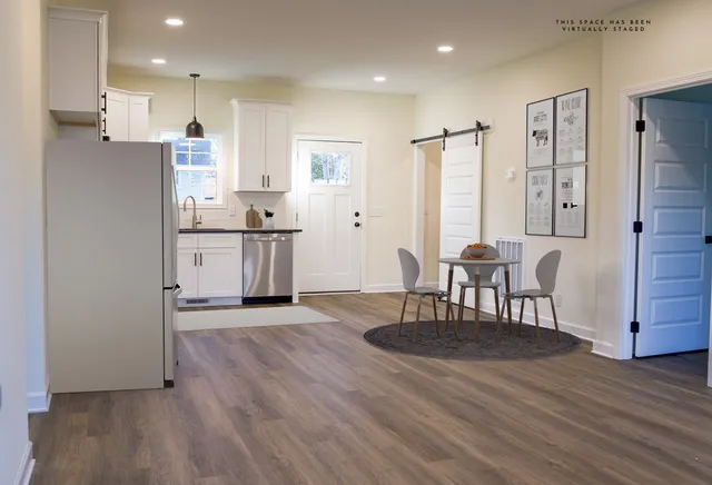 a kitchen with stainless steel appliances granite countertop a stove refrigerator a dining table and chairs with wooden floor