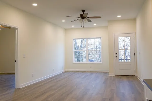 a view of an empty room with a window and wooden floor