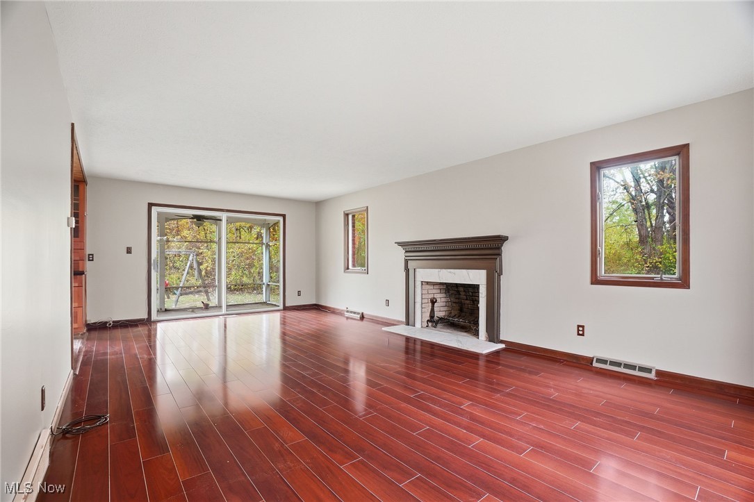 11710 Butternut Road Chardon, OH 44024 - Photo 14 of 48 Unfurnished living room featuring healthy amount of natural light, a fireplace with raised hearth, dark wood-style flooring, and baseboard heating