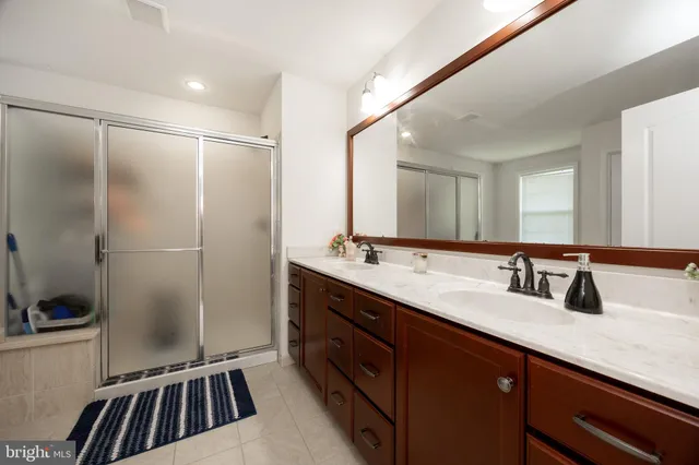 a bathroom with a double vanity sink a mirror and a shower
