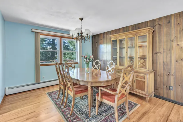 a dining room with furniture wooden floor a chandelier and a rug