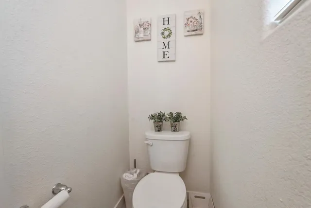 a white toilet sitting next to a white wall