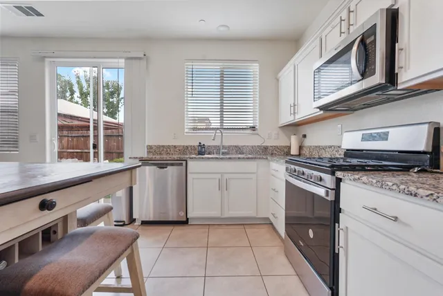 a kitchen with granite countertop a sink a stove and cabinets