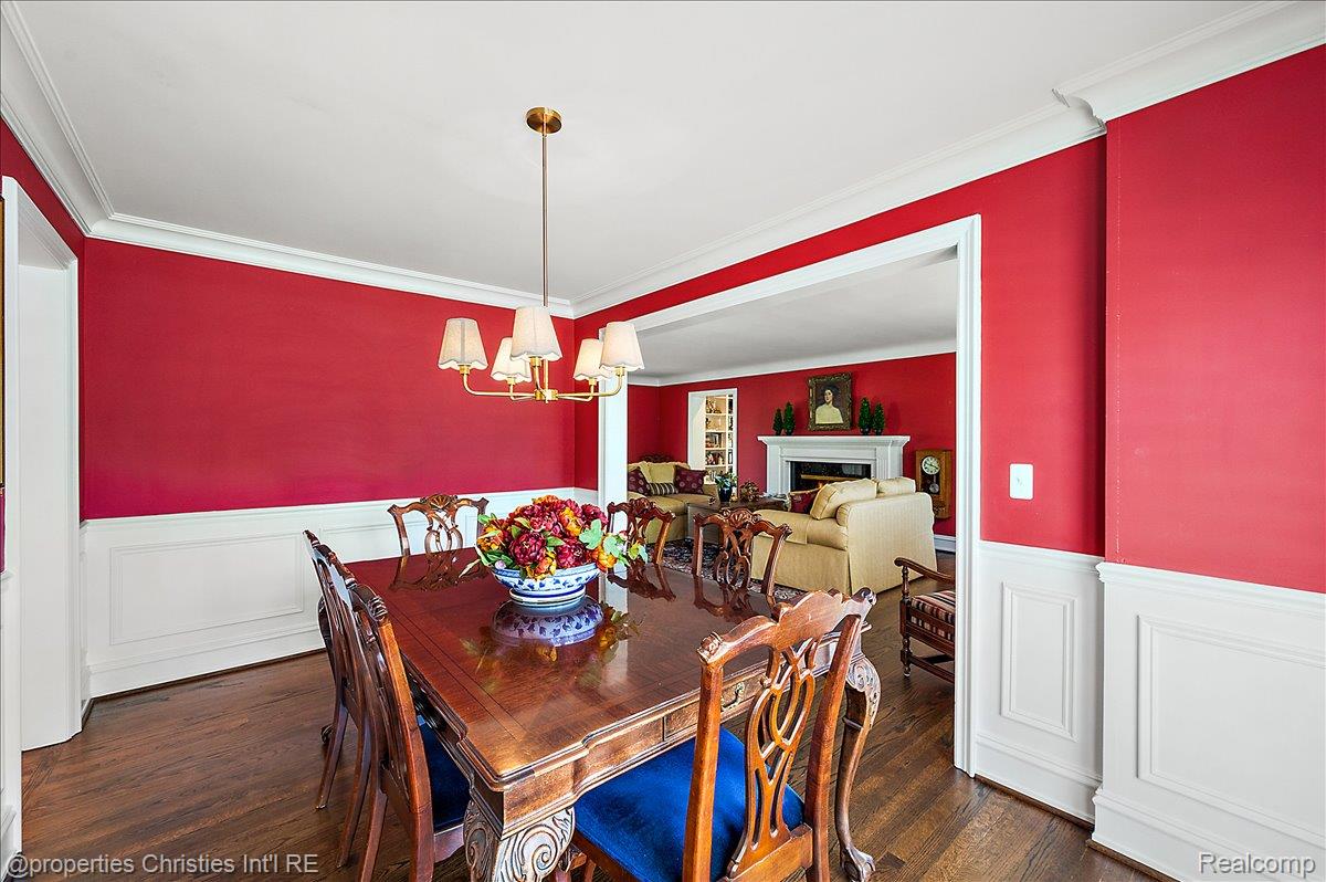 135 Clifton Road Bloomfield Hills, MI 48301 - Photo 18 of 77 Formal dining area featuring hardwood flooring, white crown molding, white wainscoting, and a brass-tone chandelier