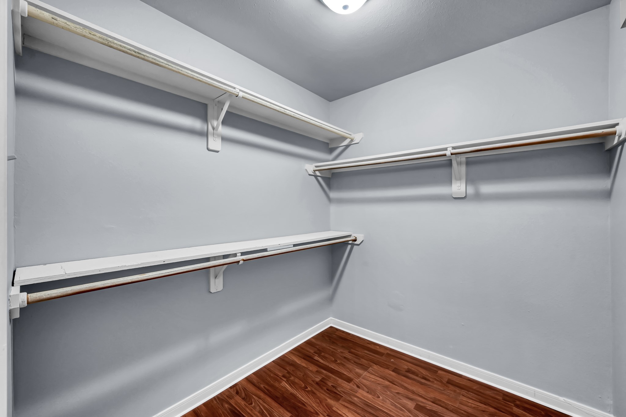 7811 Holly Berry Court Cypress, TX 77433 - Photo 15 of 24 Spacious walk-in closet with ample shelving and hanging space, featuring clean, light-colored walls and rich wood flooring.