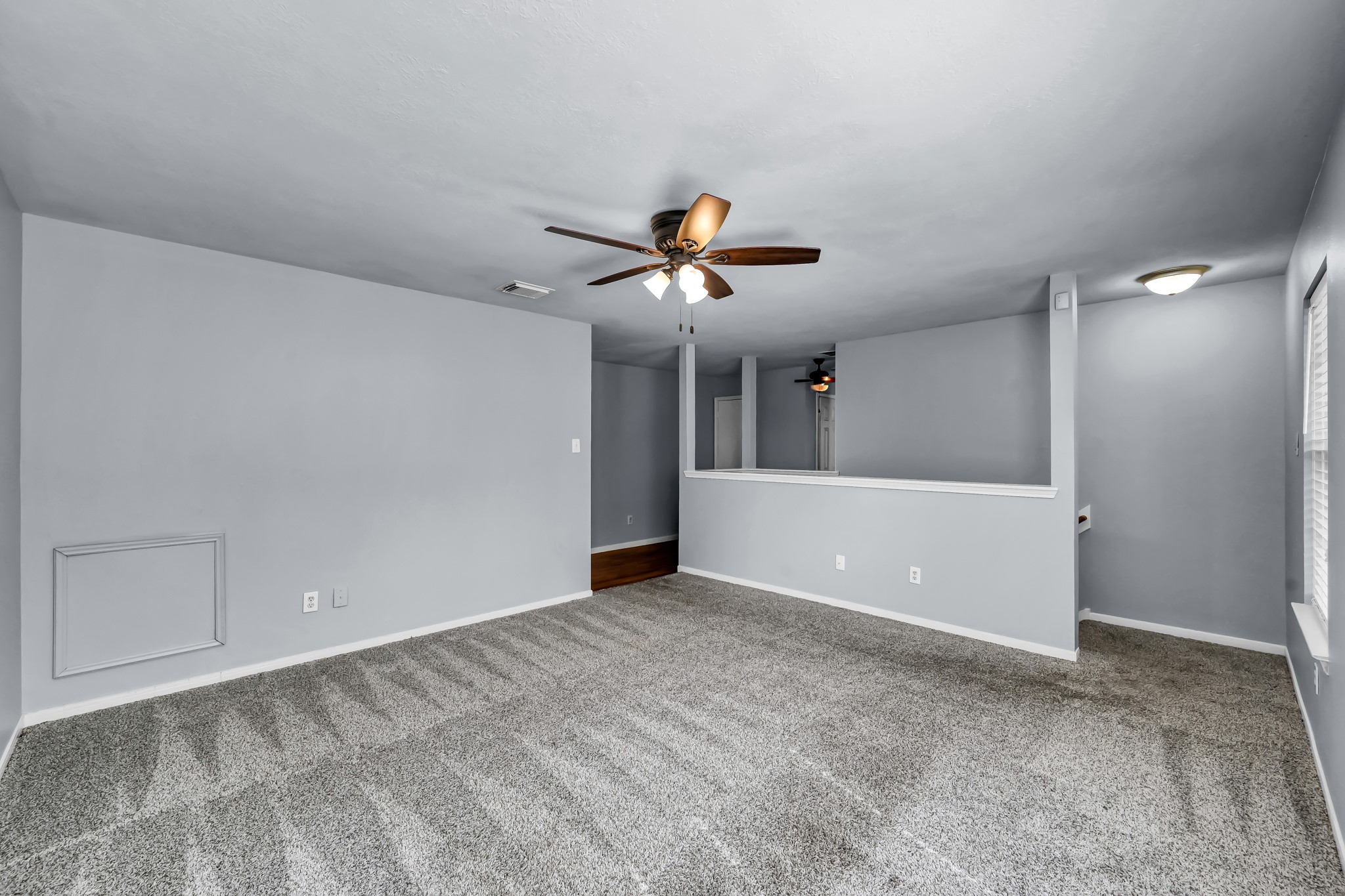 7811 Holly Berry Court Cypress, TX 77433 - Photo 16 of 24 This room features fresh gray walls, plush carpeting, and a ceiling fan for comfort. A partial wall separates spaces, enhancing an open layout ideal for flexible use.