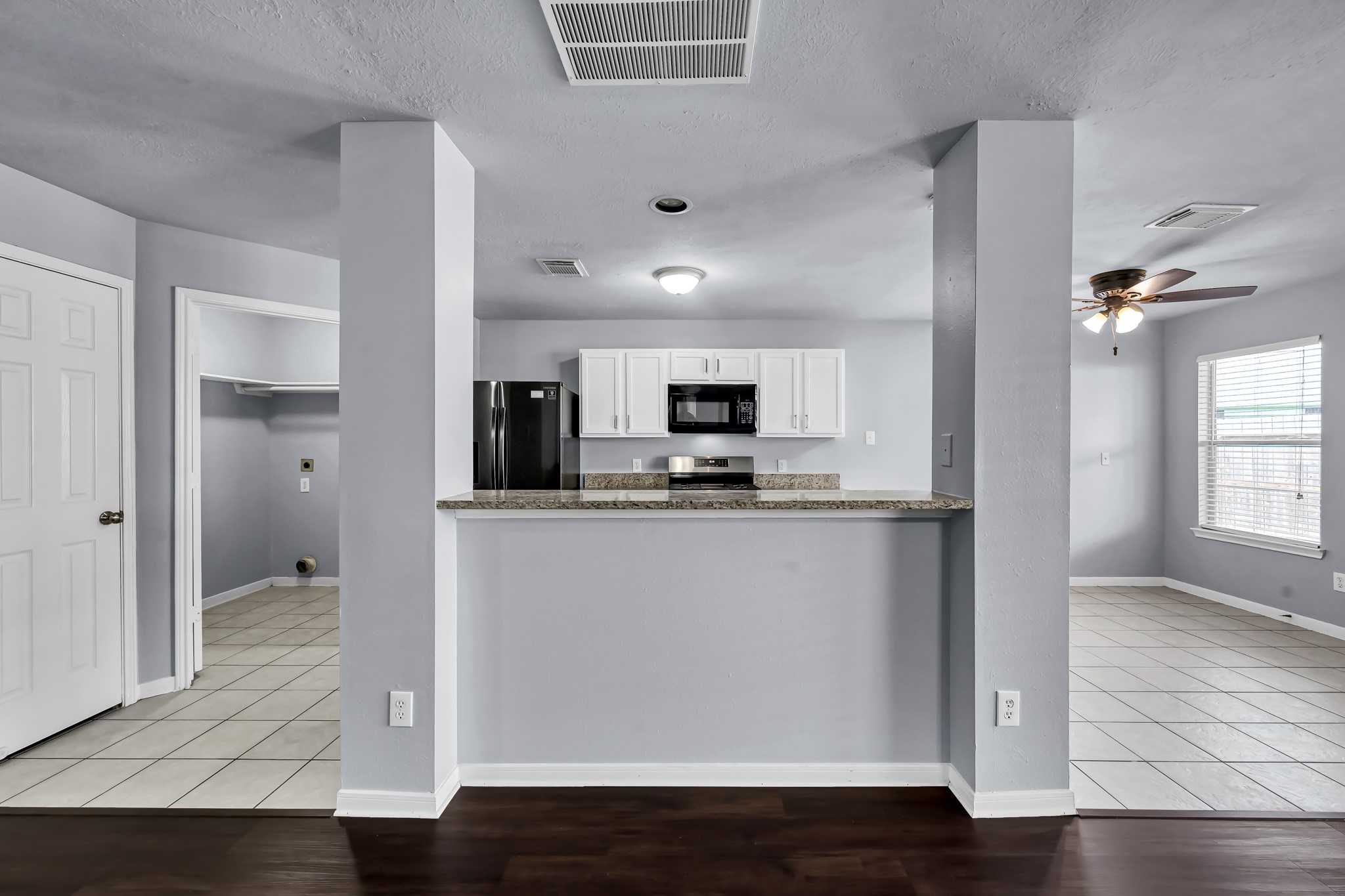 7811 Holly Berry Court Cypress, TX 77433 - Photo 7 of 24 This photo showcases a modern kitchen with granite countertops, white cabinetry, and stainless steel appliances. The open layout connects to a dining area with tile flooring and a ceiling fan, providing a bright and functional space.