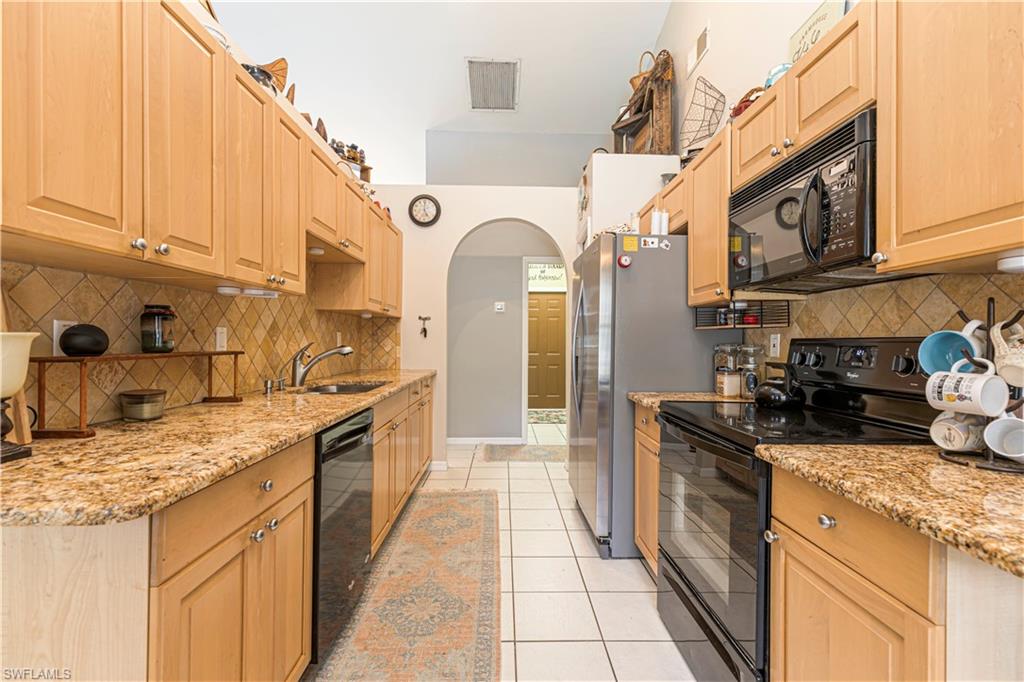 4065 10th Avenue Southeast Naples, FL 34117 - Photo 8 of 32 a kitchen with stainless steel appliances granite countertop a sink and cabinets