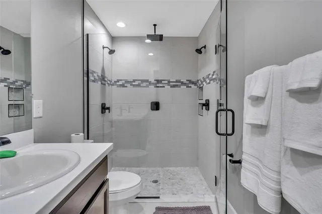 a bathroom with a granite countertop sink a toilet and shower