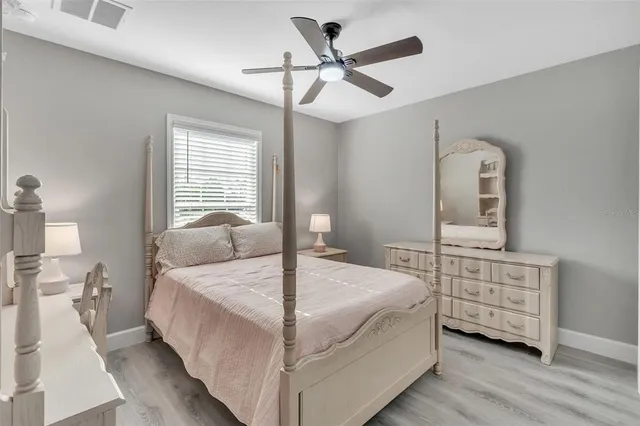 a bedroom with a bed a dresser and wooden floor