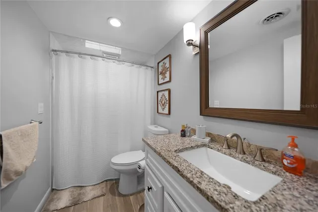 a bathroom with a granite countertop sink toilet and shower